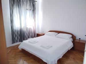 a bedroom with a white bed and a window at Apartman Perkovic in Šibenik