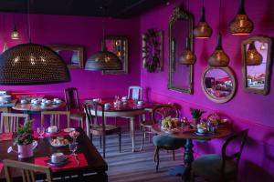 a restaurant with pink walls and tables and mirrors at Hôtel Le Grand Barnum in Francheville