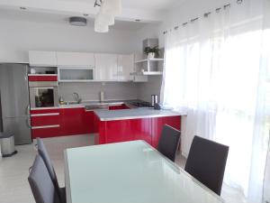 a kitchen with red cabinets and a white table and chairs at Apartman Perkovic in Šibenik