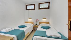 two beds in a room with white walls and blue pillows at La Maranita Apartment in La Maddalena