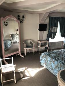 1 dormitorio con cama, espejo y silla en LE CABOUILLET en LʼIsle-Adam