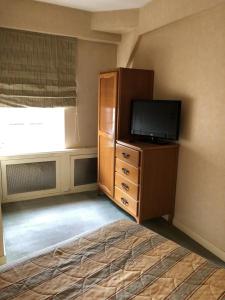 a living room with a tv and a dresser with a flat screen at LE CABOUILLET in LʼIsle-Adam