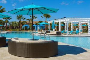 ein Pool mit blauen Sonnenschirmen neben einem Resort in der Unterkunft Lovely 5BR4BA w Private Heated Pool BBQ Grill in Kissimmee