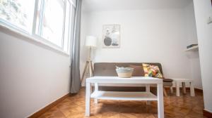 een woonkamer met een witte tafel en een stoel bij La casa del muro con vistas al mar in A Guarda