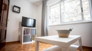 een woonkamer met een witte tafel en een tv bij La casa del muro con vistas al mar in A Guarda