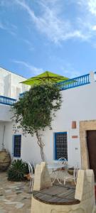 a patio with a table and a green umbrella at Dar Michèle Djerba in Houmt Souk