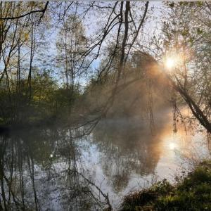 un río nebuloso con el sol reflejándose en el agua en River place, en Villemeux-sur-Eure
