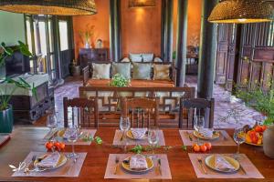 uma mesa de madeira com pratos de comida e copos de vinho em Pao Homes - An Hai Villa, Family-Friendly Villa with Pool em Hoi An