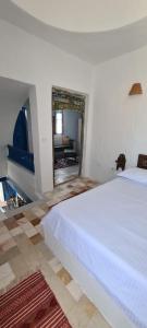 a bedroom with a white bed and a mirror at Dar Michèle Djerba in Houmt Souk