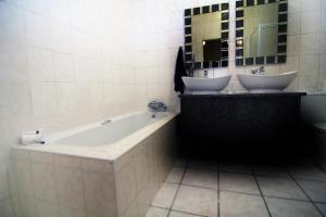 ein Badezimmer mit 2 Waschbecken und einer Badewanne in der Unterkunft Fuhri Road Apartments Madison House in Alberton