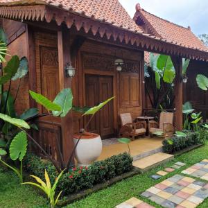 Casa de madera con porche con mesa y sillas en La Tavisa Hotel Borobudur en Magelang