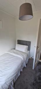 a white bed in a room with a lamp at Home in Monkstown in Monkstown