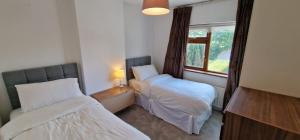 a small room with two beds and a window at Home in Monkstown in Monkstown