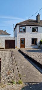 a white house with a brown door and a driveway at Home in Monkstown in Monkstown