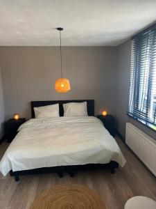 Un dormitorio con una gran cama blanca y una lámpara de araña. en Casa Xabia, en Zaandam