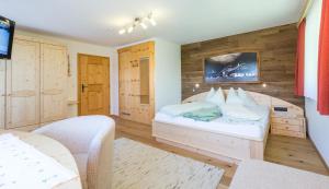Schlafzimmer mit einem weißen Bett und Holzwänden in der Unterkunft Pension Glöshof in Ramsau am Dachstein