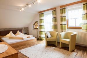 a bedroom with a bed and two chairs and a table at Pension Glöshof in Ramsau am Dachstein