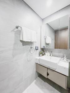 La salle de bains blanche est pourvue d'un lavabo et d'un miroir. dans l'établissement Apartment 1BR-FL24th-R105 Building-Vinhomes Ocean Park, à Hanoï