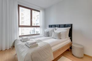 a bedroom with a large white bed with a window at Downtown Apartments Garnizon in Gdańsk