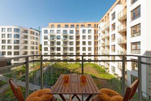 a wooden table on a balcony with a view of buildings at Downtown Apartments Garnizon in Gdańsk