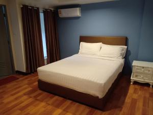 um quarto com uma cama com lençóis brancos e uma parede azul em Airport A1 Hotel em Chiang Mai