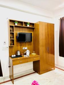 Habitación con escritorio de madera y TV. en SRH HOTEL, en Greater Noida