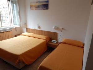 una camera d'albergo con due letti e una finestra di HOTEL MILANO a Loano