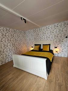 um quarto com uma grande cama branca com almofadas amarelas em Ferme La Joye em Houffalize