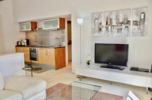 een woonkamer met een tv en een keuken bij maison bertuli Oliviers Aircon, heated saltwater Pool, 2 Bedrooms in Oppède