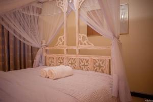 a bedroom with a canopy bed with two towels on it at Warm & Cozy 2-Br Apartment. 10 mins from City Centre in Nairobi