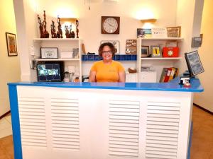 a woman standing behind a blue and white counter at Hotel MiraBela in Santa Maria