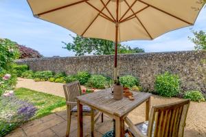 a wooden table with an umbrella on a patio at Hop Cottage in East Dean