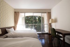una camera d'albergo con due letti, una scrivania e una finestra di B&B Retreat志摩 a Shima