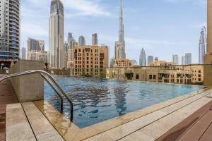 a swimming pool on top of a building with a city skyline at Waves Holiday Home - Chic Apartment With Dubai Skyline Views in Dubai