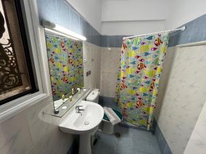 a bathroom with a sink and a shower curtain at Lerna Rooms in Myloi