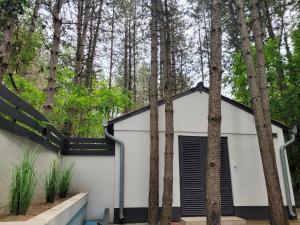 a white shed with a black roof in the woods at Ambiente in Kiskunhalas