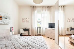 a white bedroom with a large bed and a television at CASA TILDE Barbaresco in Barbaresco