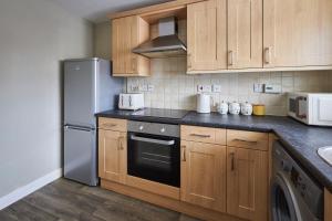 Una cocina con gabinetes de madera y un refrigerador de acero inoxidable. en Host & Stay - Beachcomber's Rest, en Seahouses 10 fotos más