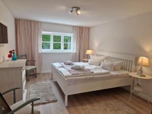 - une chambre avec un grand lit blanc et une fenêtre dans l'établissement Ferienwohnung Düne mit Kamin und 2 Bädern in Boltenhagen, à Boltenhagen