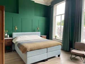 een slaapkamer met groene muren en een bed en een stoel bij Bed & Breakfast By Genck in Oudenbosch