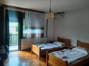 a bedroom with two beds and a window with a balcony at Privatni smještaj Radić in Teslić
