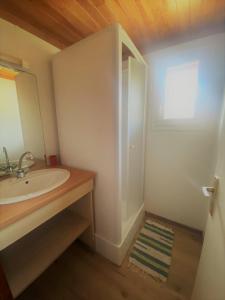 La salle de bains blanche est pourvue d'un lavabo et d'un miroir. dans l'établissement Camping familial les chalets d'Uza, à Uza