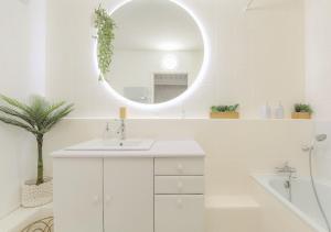 a white bathroom with a sink and a mirror at LOUISE - Studio de qualité et très cozy in Saint-Étienne