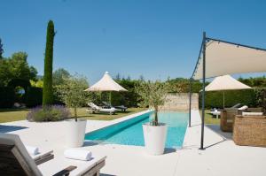 een zwembad met twee parasols en een zwembad bij maison bertuli Oliviers Aircon, heated saltwater Pool, 2 Bedrooms in Oppède