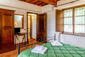 a bedroom with a bed with green sheets and a television at Casa Vacanza Il Carpignone 2 in Massa Marittima