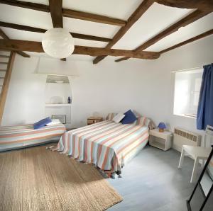 um quarto com paredes brancas e uma cama com lençóis listrados em Ancien moulin à vent du 19e siècle em Cherrueix