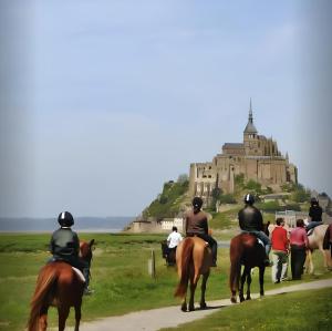 um grupo de pessoas a montar cavalos em frente a um castelo em Ancien moulin à vent du 19e siècle em Cherrueix
