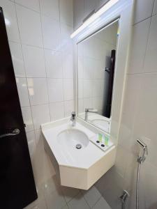 La salle de bains blanche est pourvue d'un lavabo et d'un miroir. dans l'établissement DANA HOTEL, à Charjah