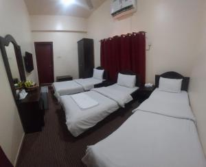 um quarto de hotel com três camas e uma cortina vermelha em DANA HOTEL em Sharjah