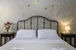 una camera da letto con un letto con lenzuola bianche e due tavoli di La Gemma del Salento a Racale